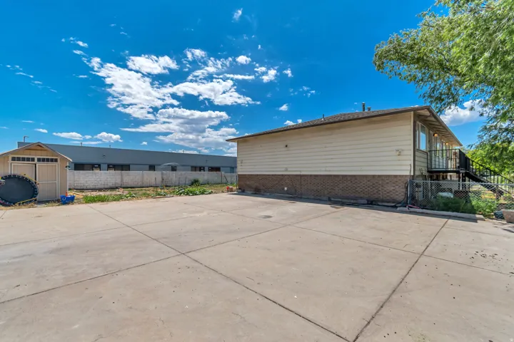 Expansive concrete patio area with a detached storage shed