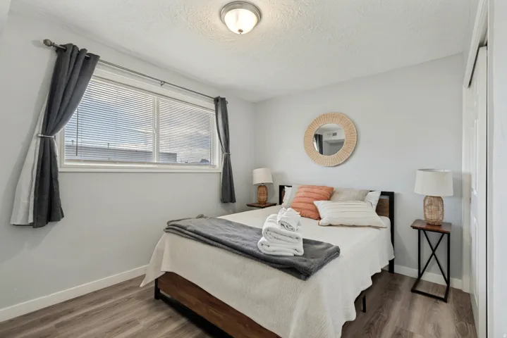 Interior room featuring a large window with blinds, wood-finish flooring, light gray walls, a flush-mount ceiling light, and a white sliding door