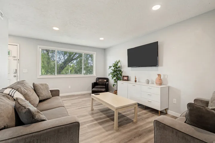 Living space featuring wood-finish flooring, recessed lighting, and a large window with horizontal blinds