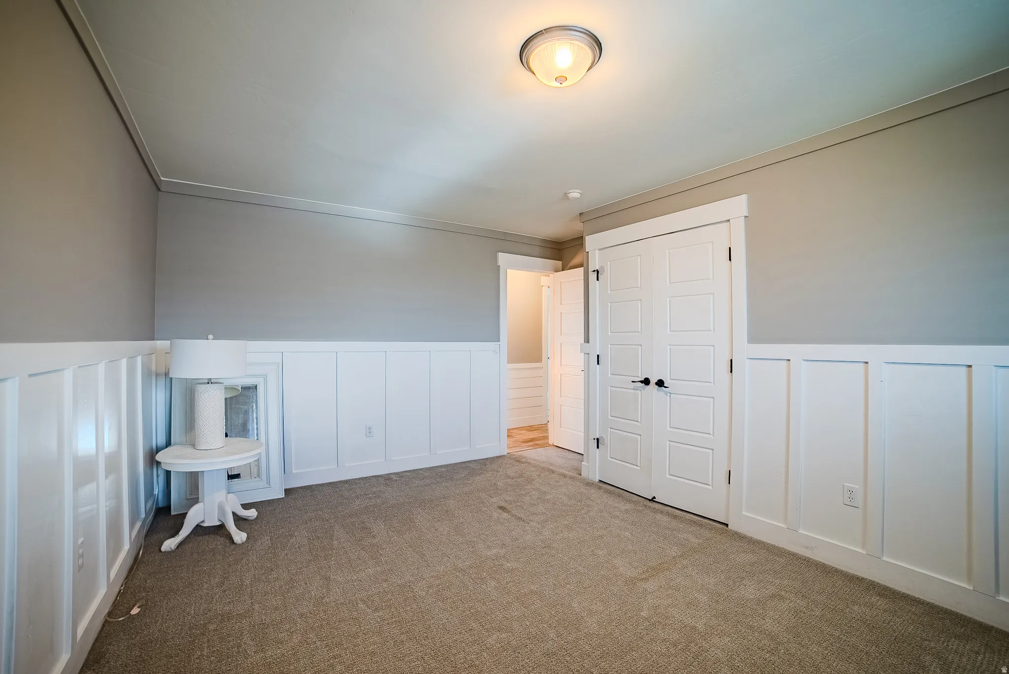 Neutral-toned carpeting paired with white wainscoting and light gray walls