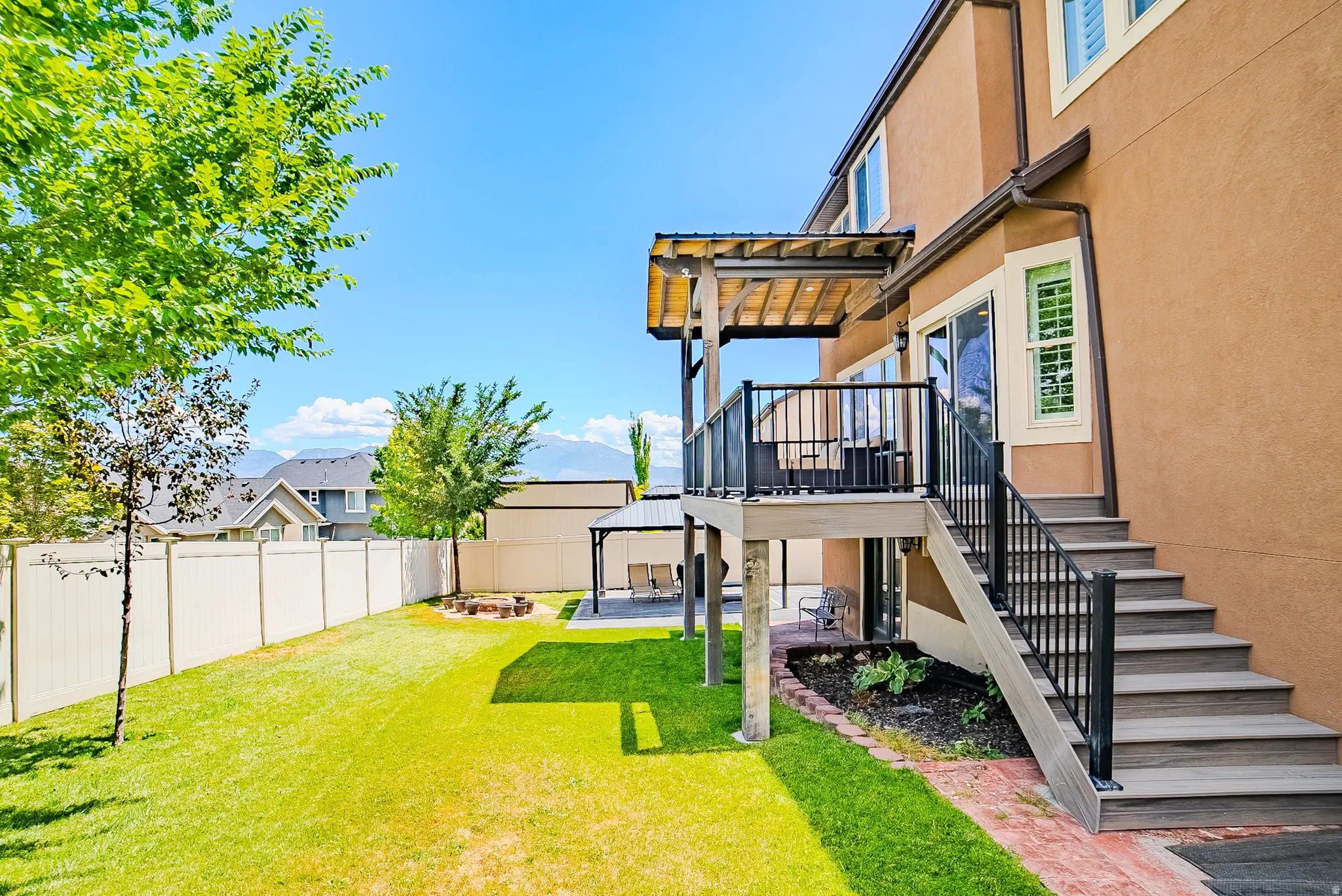 Expansive backyard featuring a multi-level deck with composite steps, a full privacy fence, and a designated fire pit area