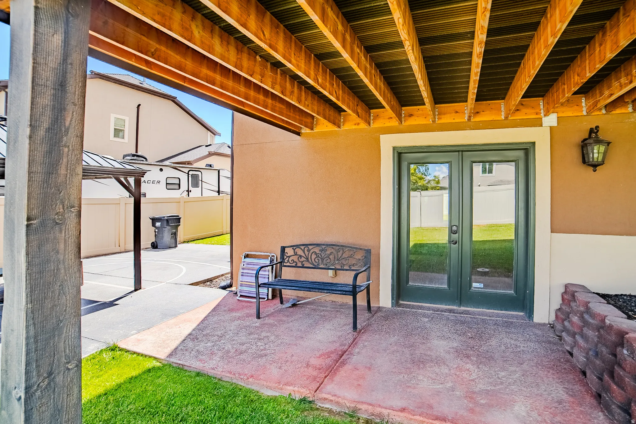 Covered patio featuring a concrete surface, exposed wood beam ceiling, and a dark green French door entry