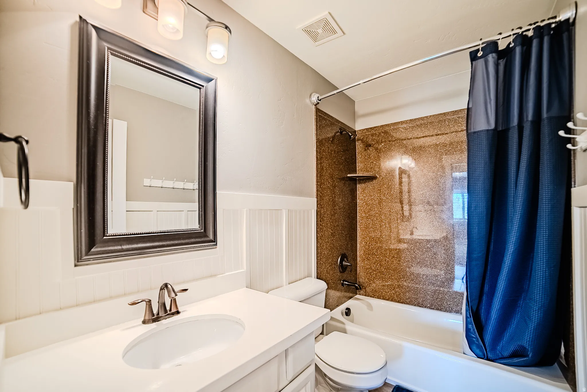 Bathroom featuring a white vanity with an undermount sink, brushed nickel faucet, and framed mirror