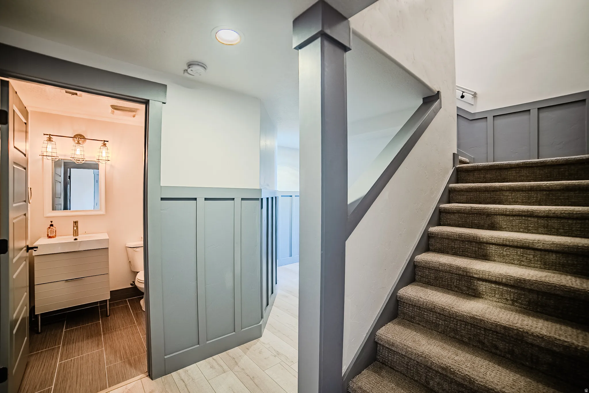 Staircase with carpeted treads and painted board and batten wall paneling