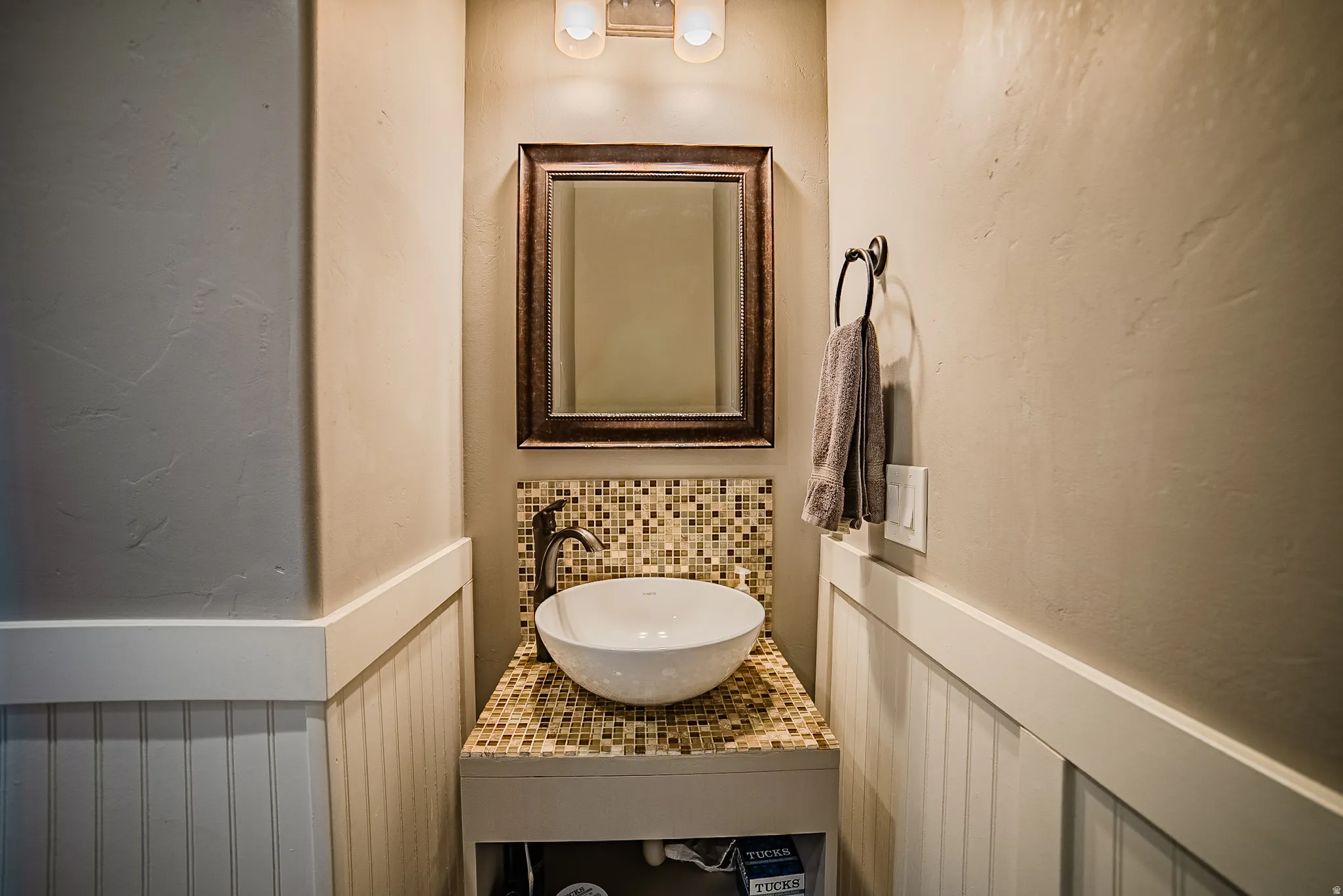 Vanity with a white vessel sink, mosaic tile countertop, and dark bronze faucet