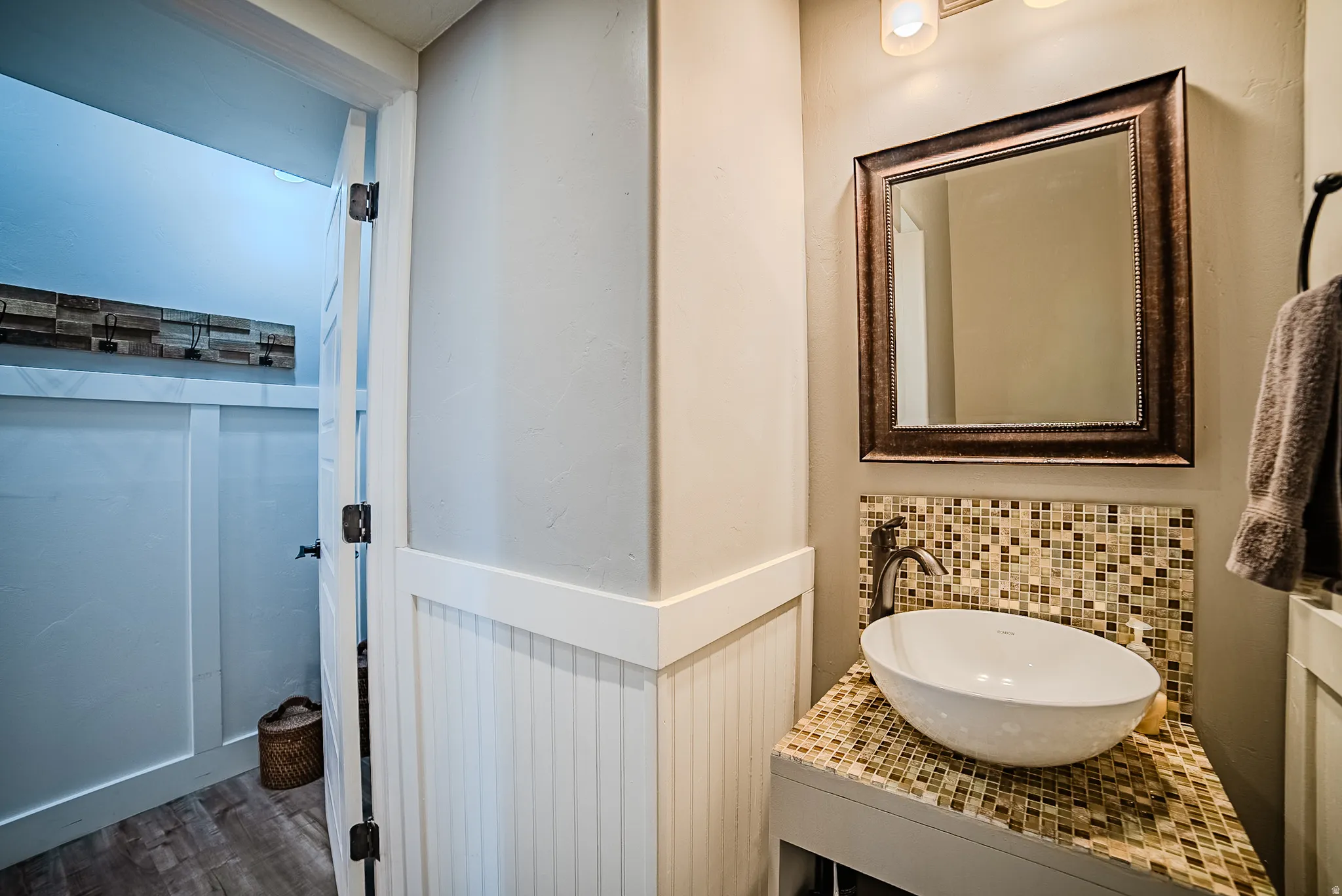 Bathroom vanity featuring a vessel sink, mosaic tile countertop, and an ornate framed mirror