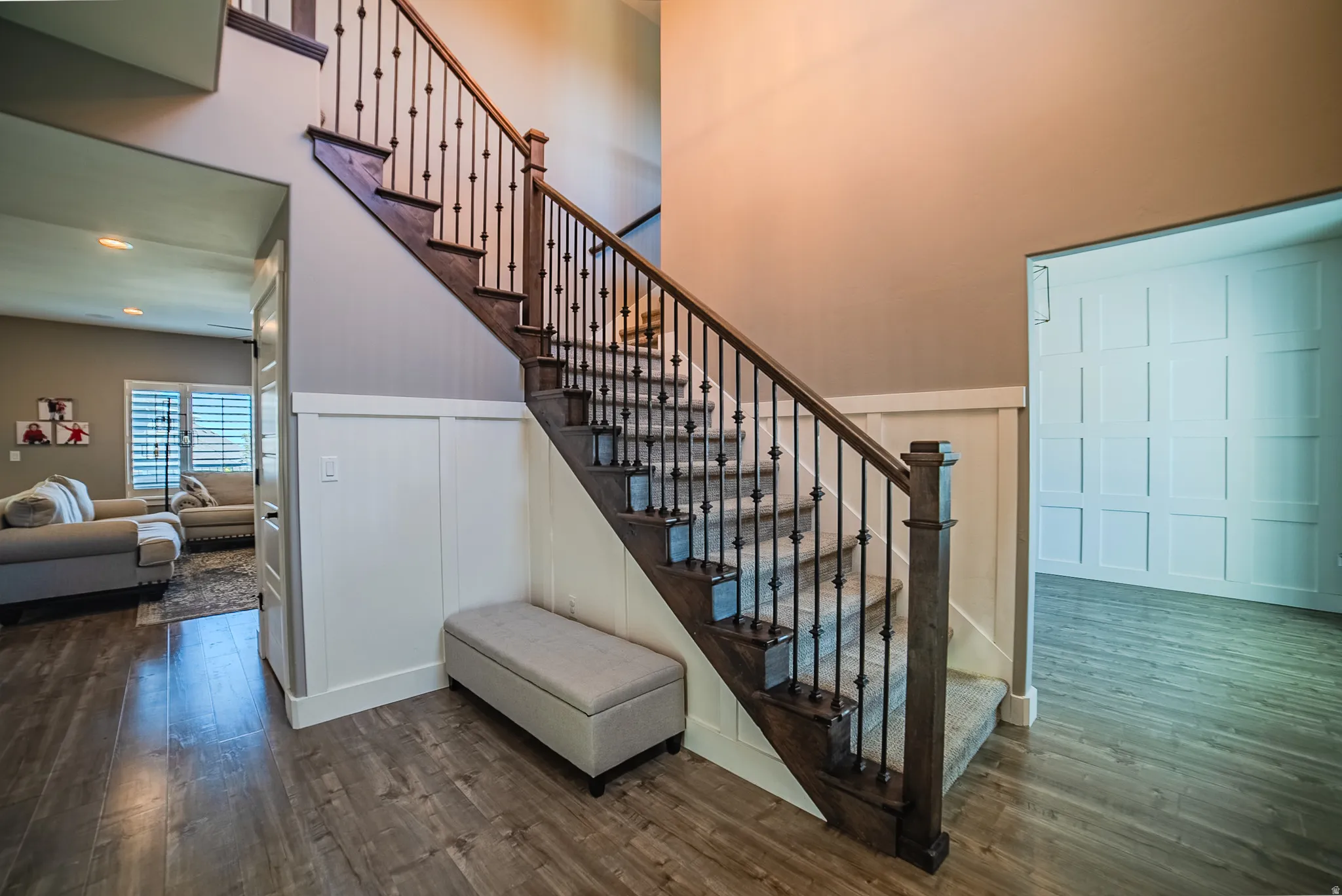 Grand staircase featuring dark wood newel posts, handrails, and wrought iron balusters