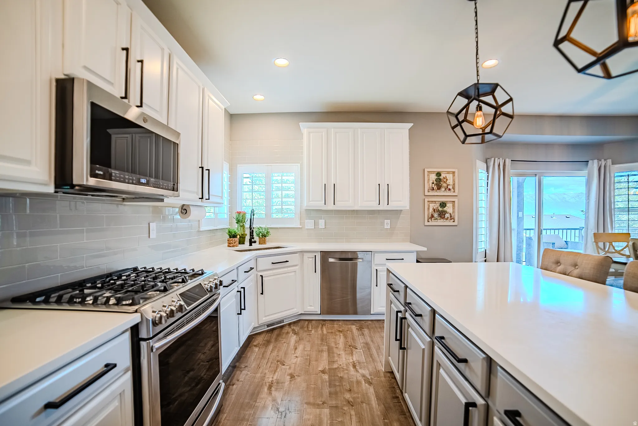 Modern kitchen featuring white cabinetry, a large center island, stainless steel appliances, a subway tile backsplash, and wood-finish flooring