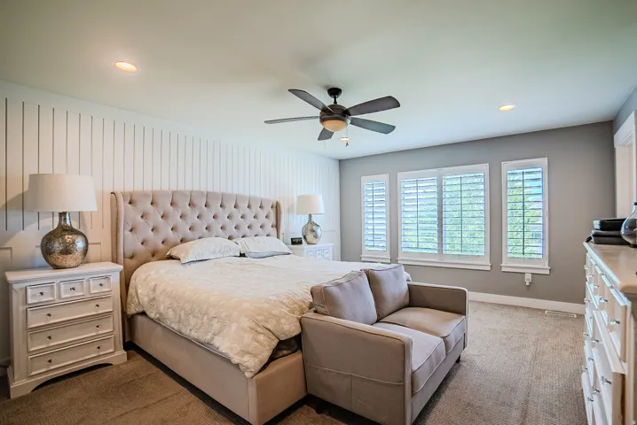 Bedroom featuring a ceiling fan, recessed lighting, and wall paneling