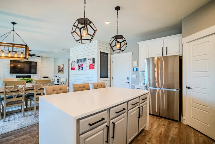 Kitchen island with a white countertop and light grey cabinetry featuring black hardware