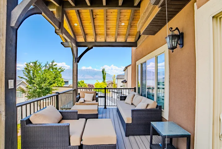 Covered balcony featuring a wood-plank ceiling, black metal railings, and stucco exterior walls