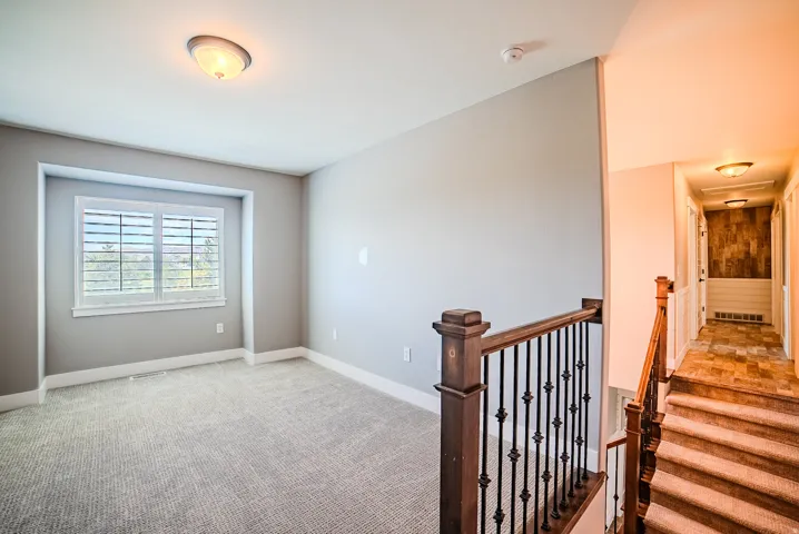 Upper-level room featuring plush carpeting, a large window with white blinds, and ceiling-mounted lighting