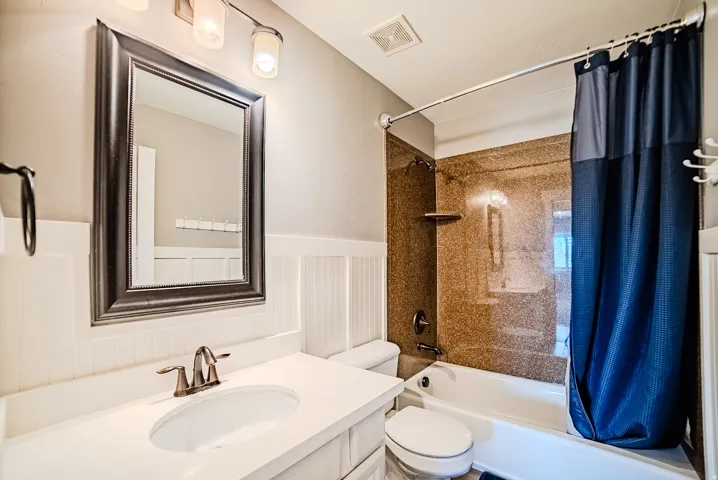 Bathroom featuring a white vanity with an undermount sink, brushed nickel faucet, and framed mirror