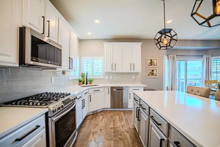 Modern kitchen featuring white cabinetry, a large center island, stainless steel appliances, a subway tile backsplash, and wood-finish flooring