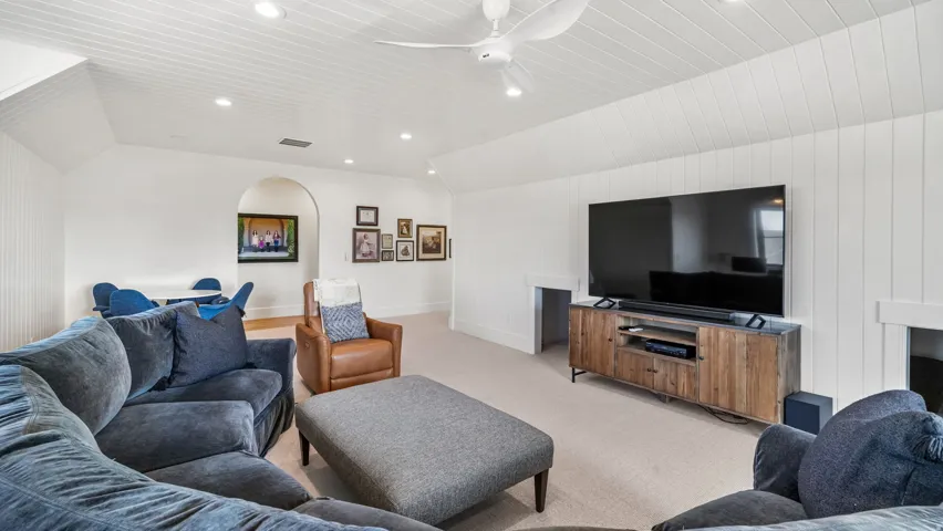Spacious entertainment area featuring vaulted ceilings, recessed lighting, and white paneled walls