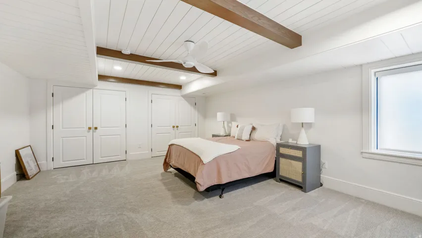 Spacious room featuring a white paneled ceiling with exposed wood beams and a ceiling fan