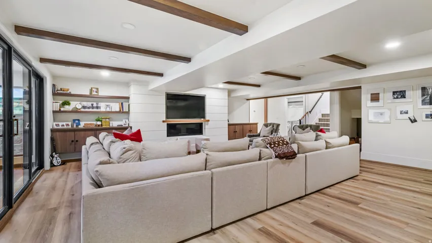 Spacious living area featuring wood-finish flooring and exposed ceiling beams