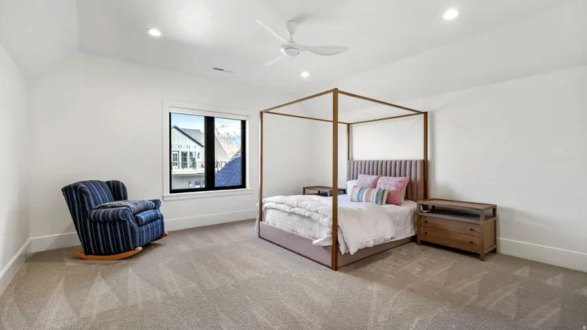 Carpeted room with vaulted ceilings and recessed lighting