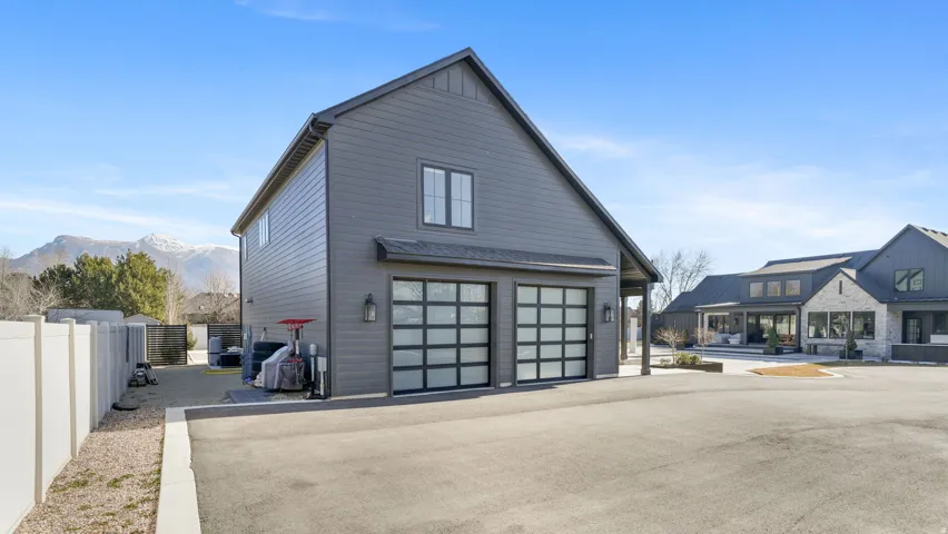 Detached two-story structure featuring dark gray siding and a black shingled roof