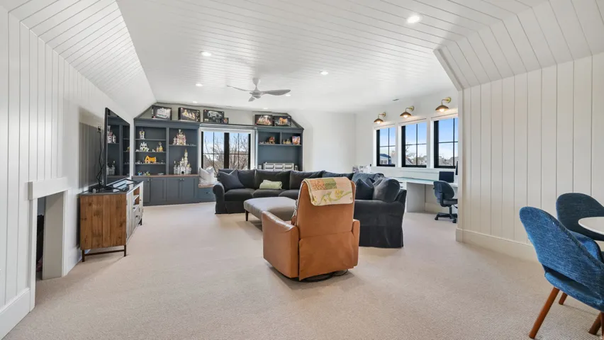 Spacious finished room featuring light carpet flooring, white shiplap walls, and a matching shiplap ceiling