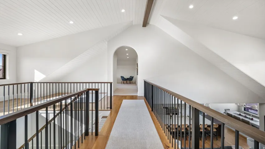 Upper-level landing featuring wood-finish flooring, a vaulted shiplap ceiling, recessed lighting, and a black metal and wood-finish railing