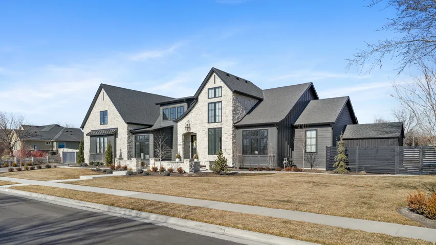 Modern farmhouse exterior featuring light-colored brick, dark vertical siding, and a dark shingle roof