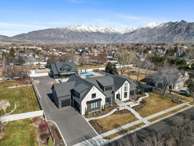 Modern farmhouse-style residence featuring a stone and dark siding exterior, a multi-car driveway, an attached garage, a detached accessory dwelling unit, and a rooftop swimming pool