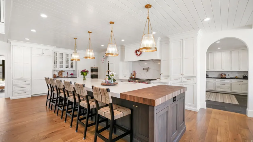 Spacious kitchen featuring an oversized island with a wood-finish countertop, plank wood-finish ceiling, light wood-finish flooring, white cabinetry, and recessed lighting
