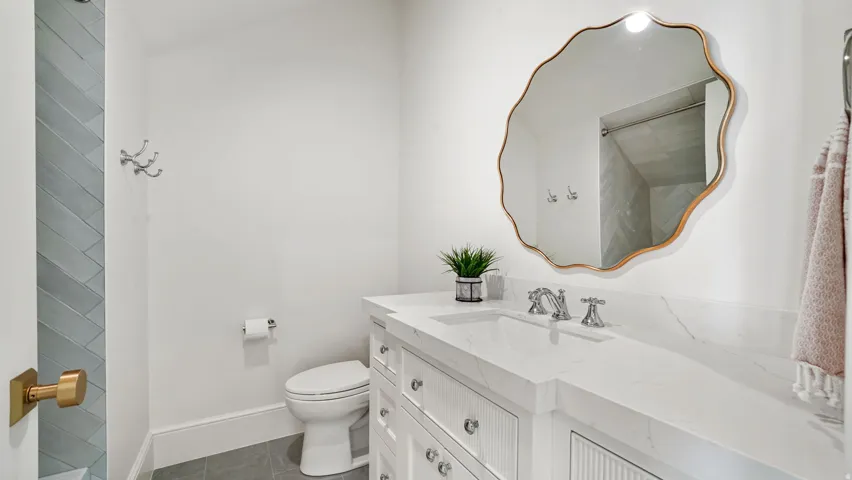 Bathroom featuring a white vanity with integrated sink, a large decorative mirror with a gold-tone frame, and a toilet