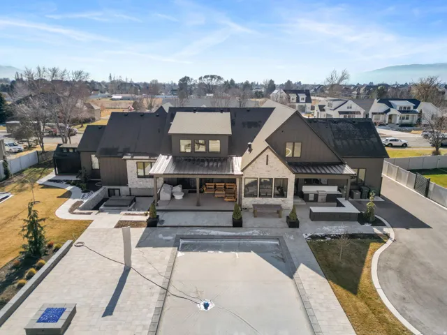 Contemporary residence featuring a covered patio, extensive paver hardscaping, a large rectangular pool, and a built-in outdoor kitchen area
