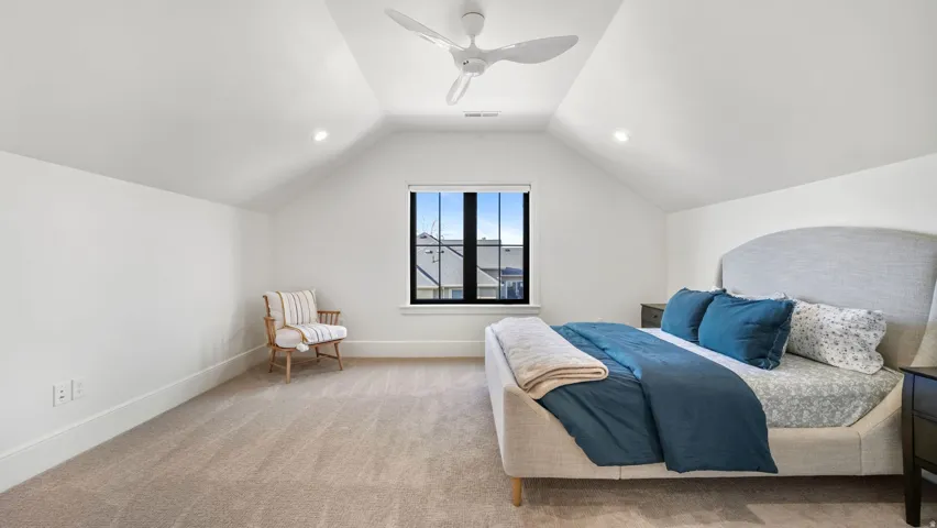 Vaulted ceiling bedroom featuring plush carpet flooring, recessed lighting, a modern ceiling fan, and a black-framed window