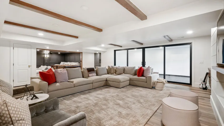 Lower level living area featuring exposed wood beams, recessed lighting, and light wood-finish flooring