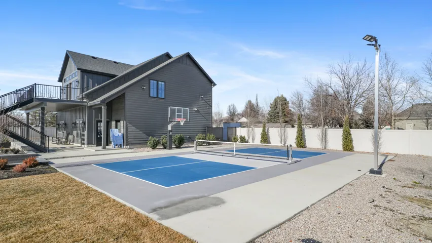 Outdoor sports court featuring blue playing surfaces, a basketball hoop, and dedicated lighting