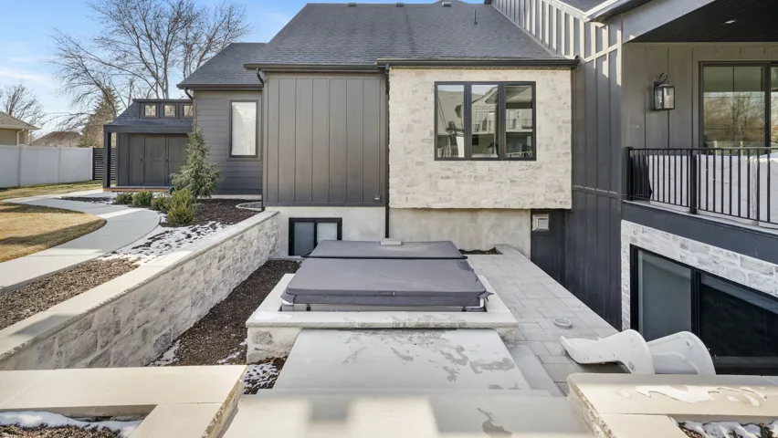 Exterior stonework and dark vertical siding complement the integrated outdoor spa area
