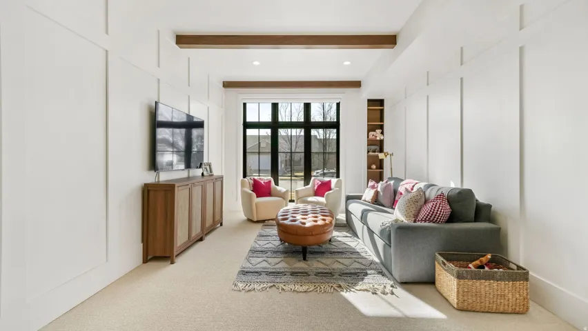 Room featuring board and batten wall paneling, a large window with dark trim, recessed lighting, and exposed ceiling beams