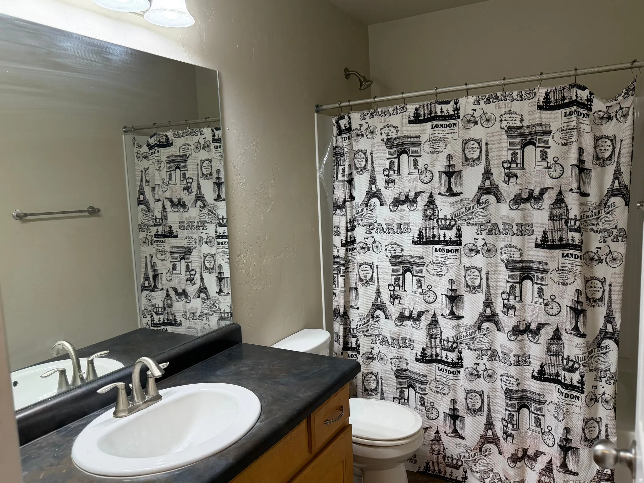 Bathroom vanity featuring an integrated sink with a brushed nickel faucet, a dark countertop, and a large wall-mounted mirror