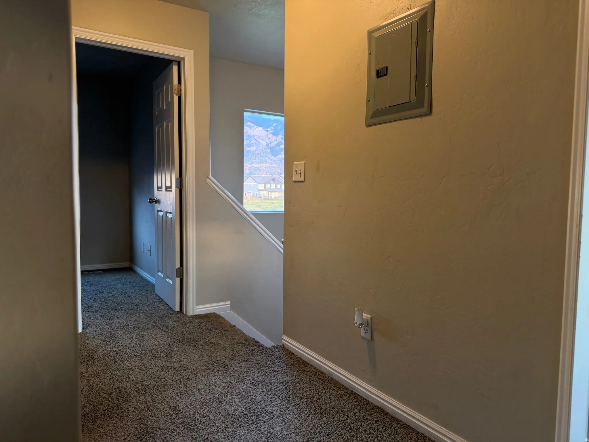 Carpeted hallway with painted walls and white baseboards
