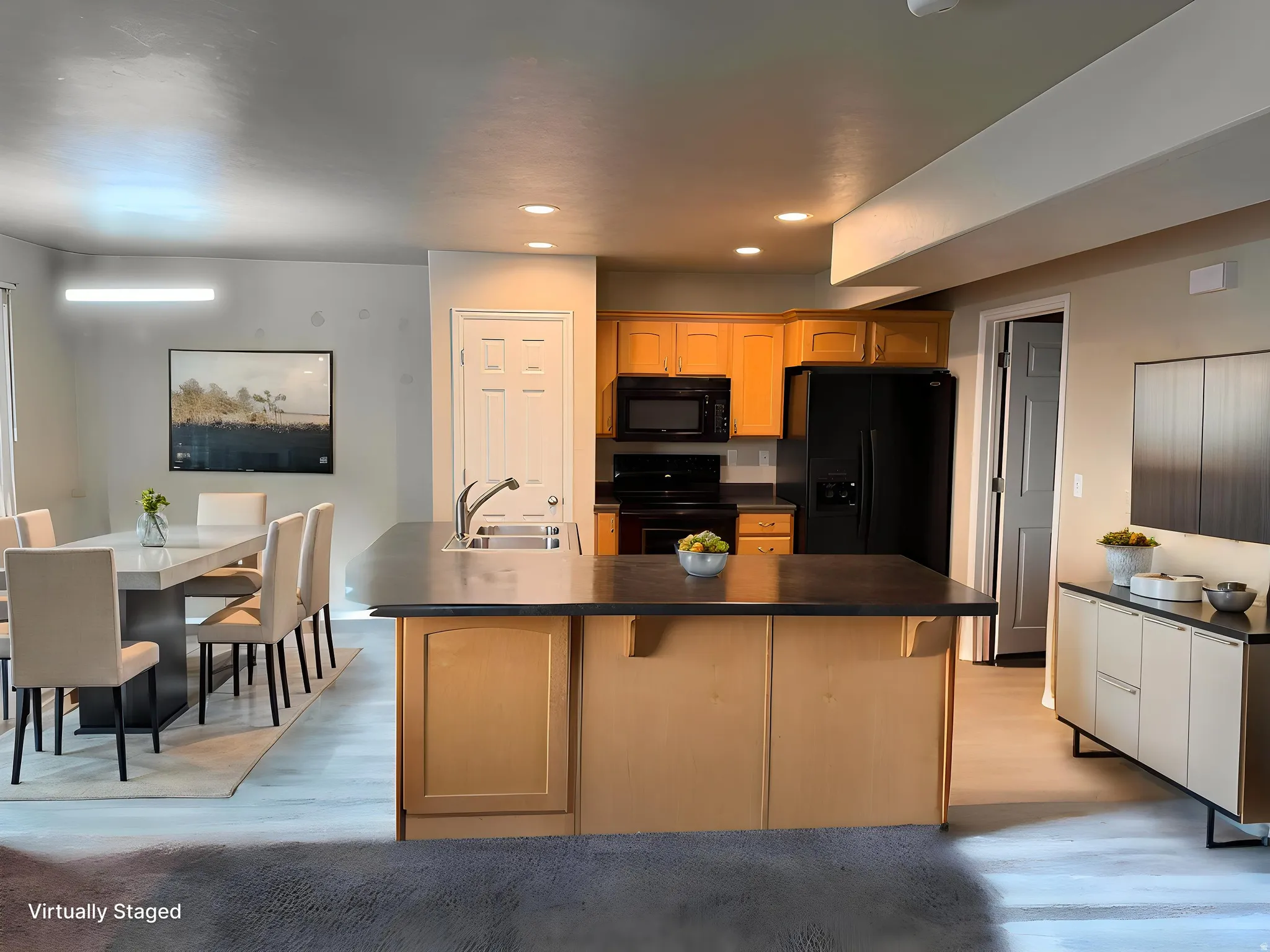 Kitchen island with integrated sink, black appliances, light wood-finish cabinetry, and recessed lightingVirtually modified