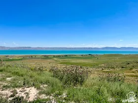 Expansive landscape featuring a large body of water, distant mountains, and varied green foliage
