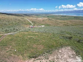 Expansive open land featuring a winding dirt road and distant water views