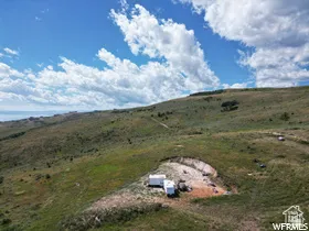 Expansive hillside property featuring natural landscaping, distant body of water, and a generous building area