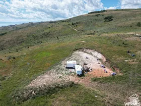 Expansive hillside lot featuring a cleared building site, established natural terrain, and distant water visible on the horizon