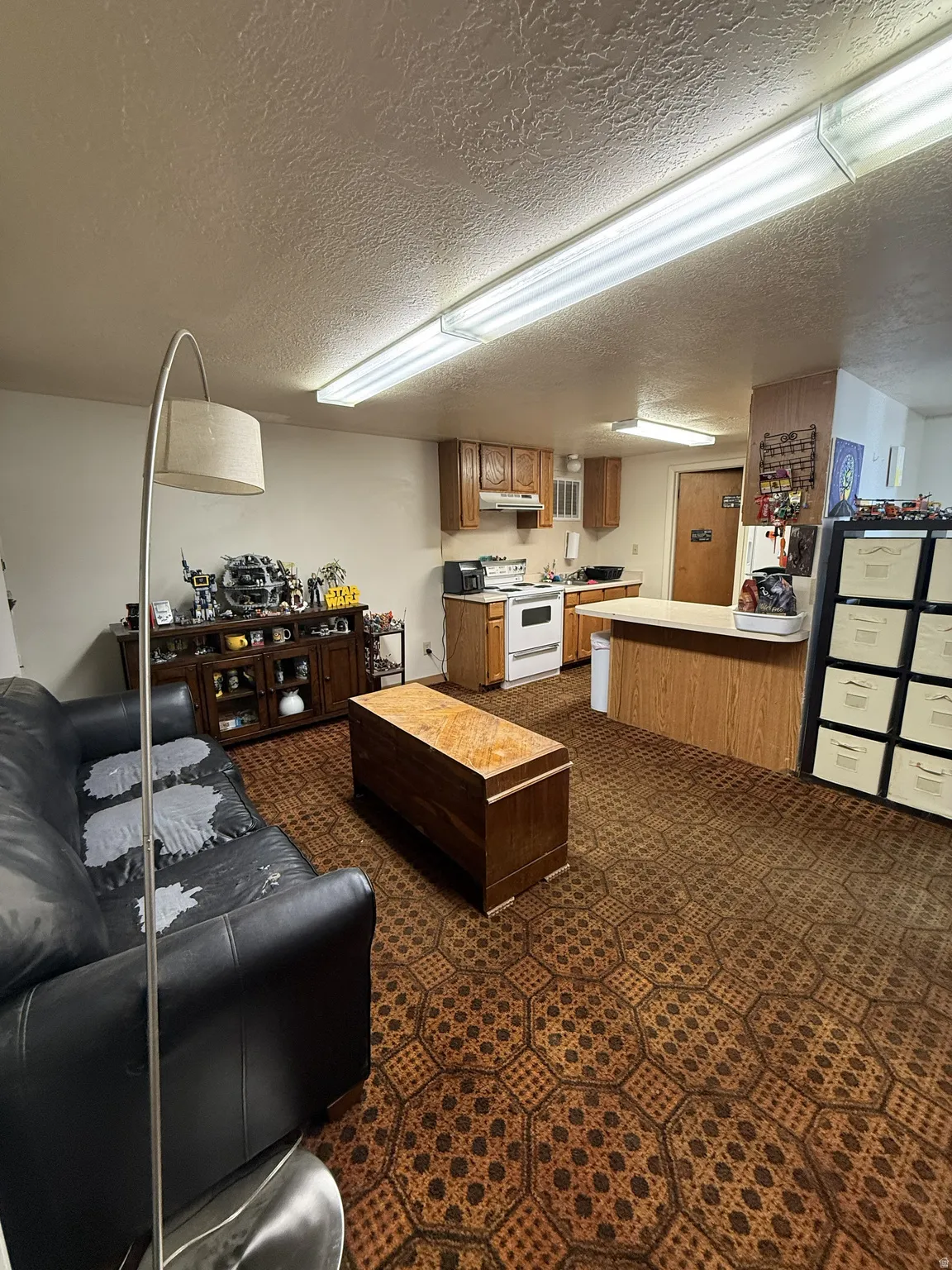 Open-concept living space featuring patterned carpet flooring and a kitchen area