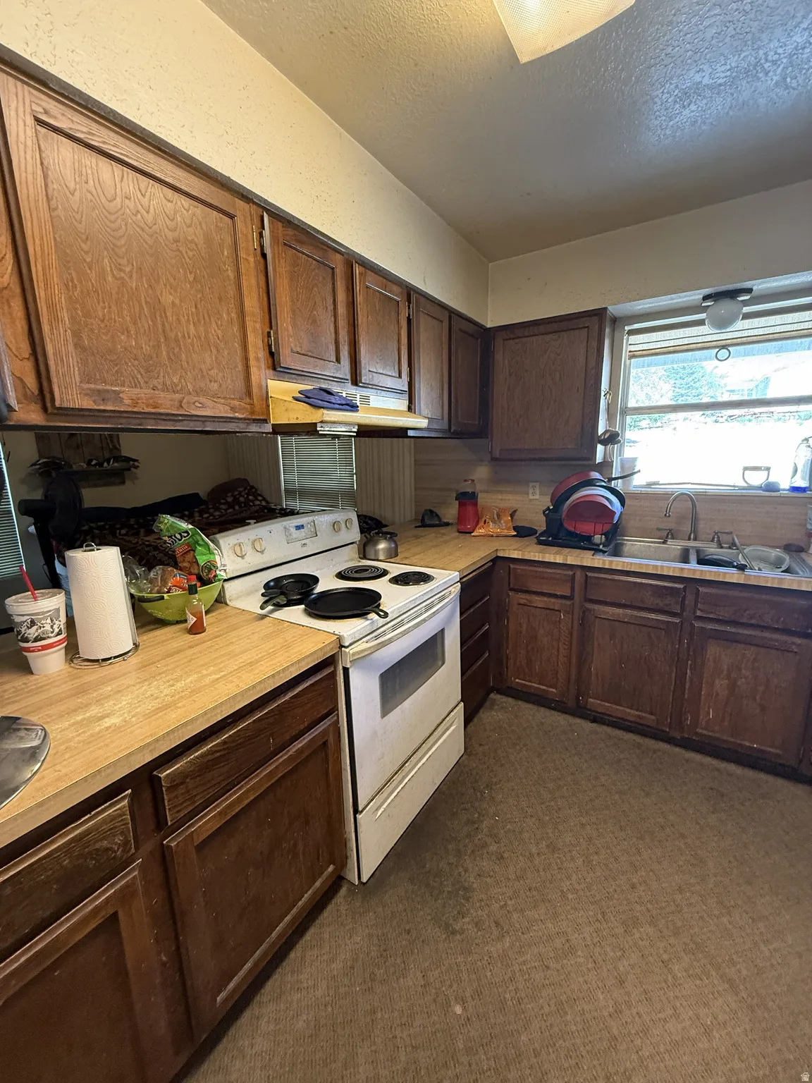 Kitchen featuring wood-finish cabinetry, light-toned countertops, and a double basin stainless steel sink