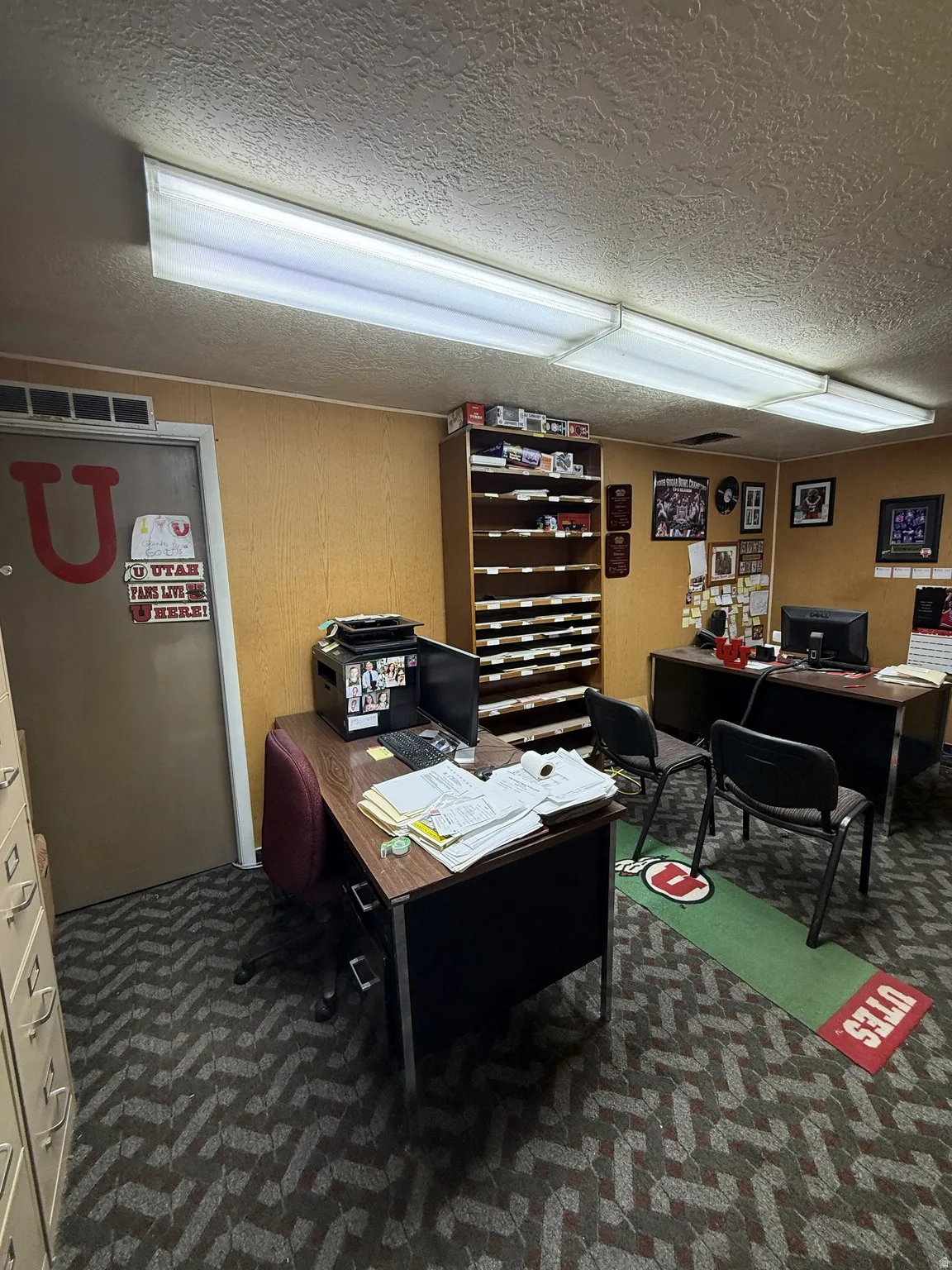 Commercial office space featuring patterned carpet flooring, fluorescent overhead lighting, and built-in shelving