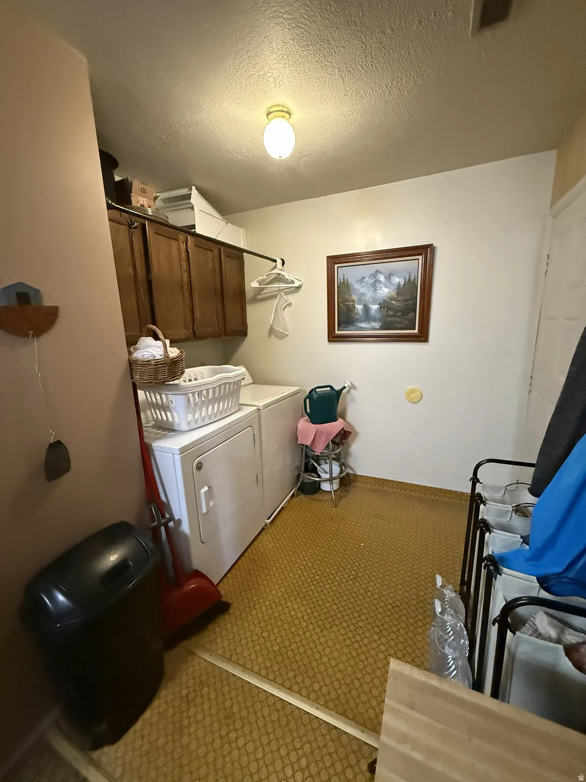 Laundry area featuring upper cabinetry, a hanging rod, and textured flooring