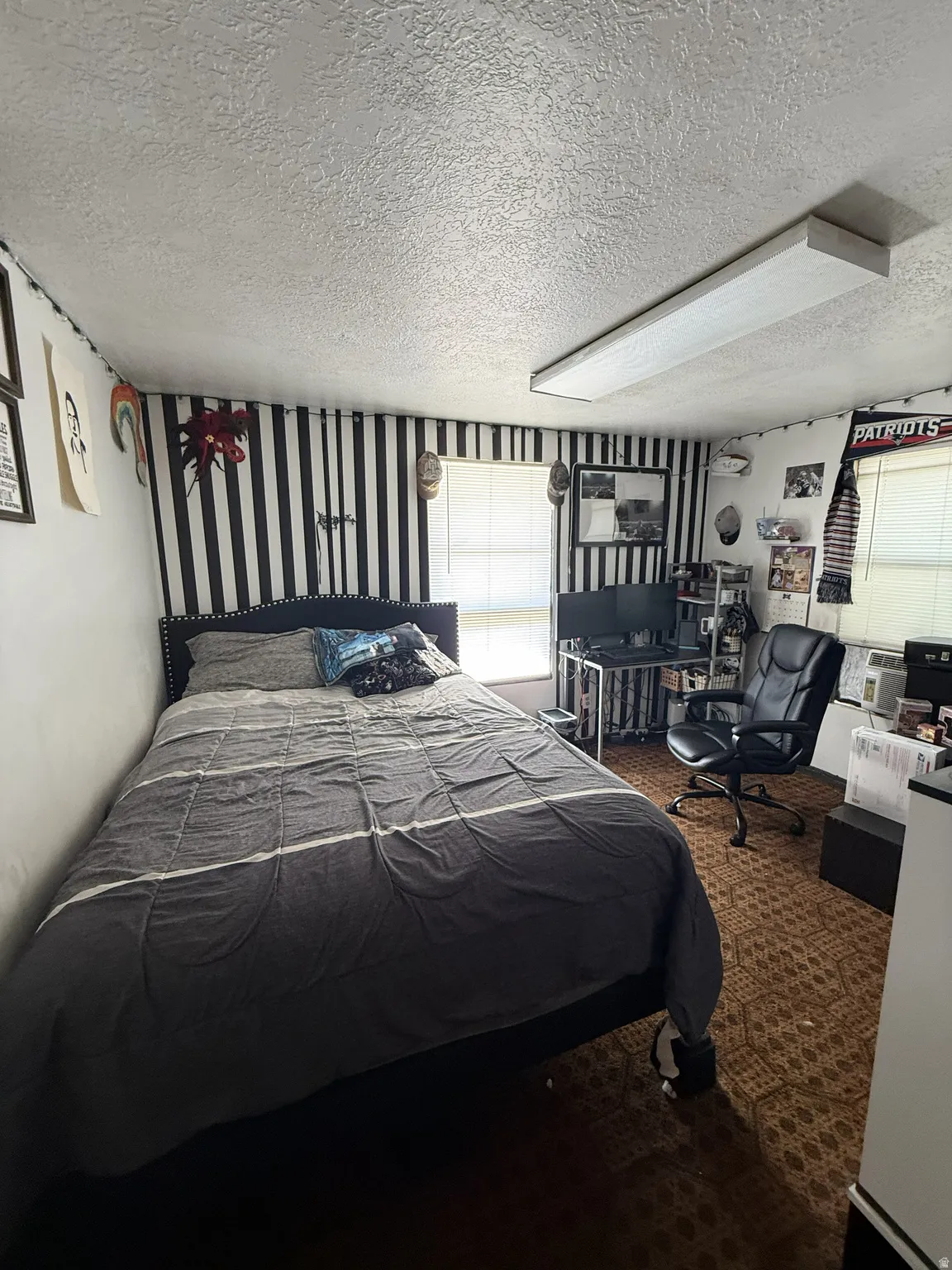 Room featuring patterned wall covering and textured ceiling