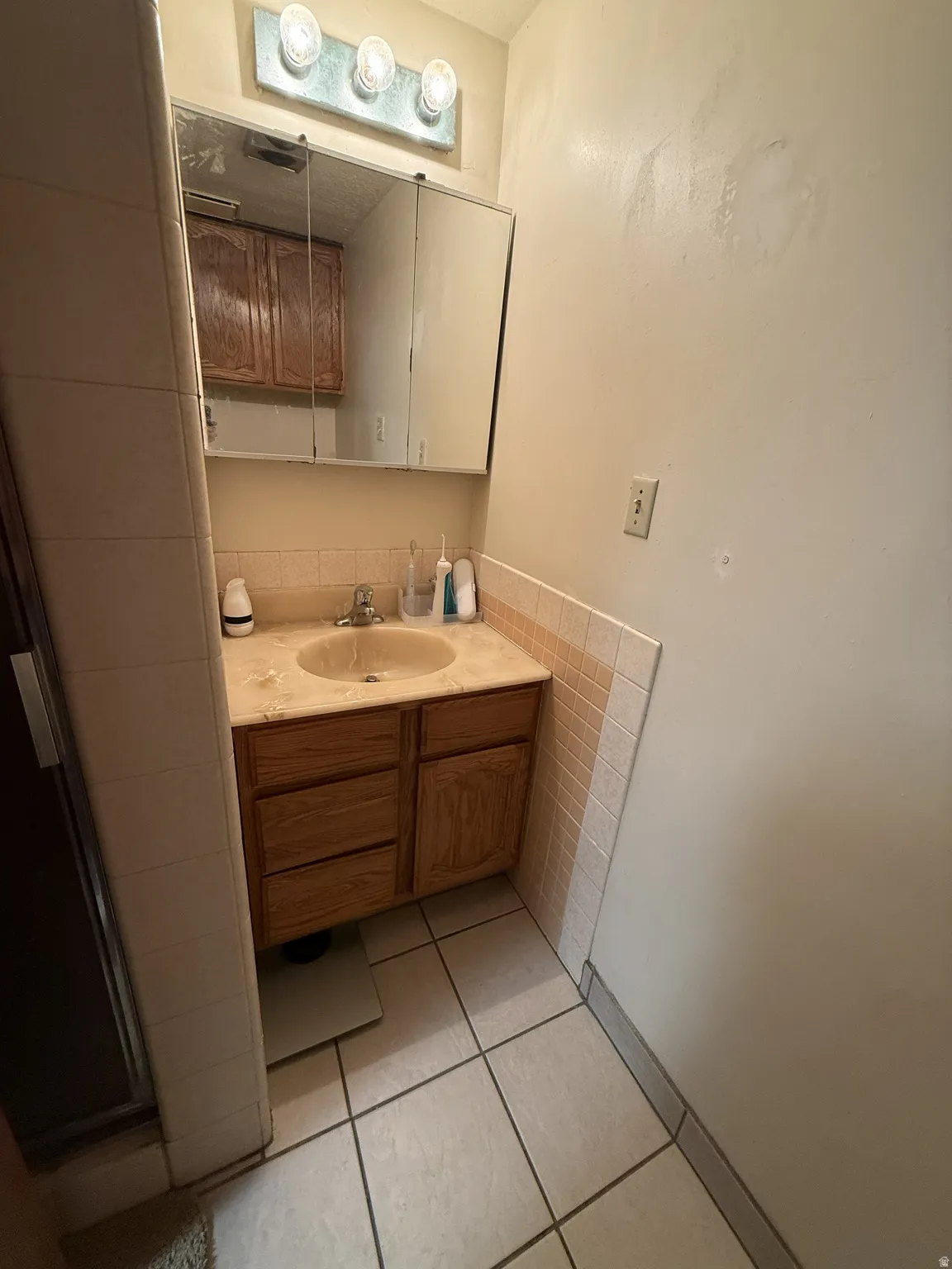 Bathroom vanity with a built-in sink, wood-finish cabinetry, and a mirrored medicine cabinet