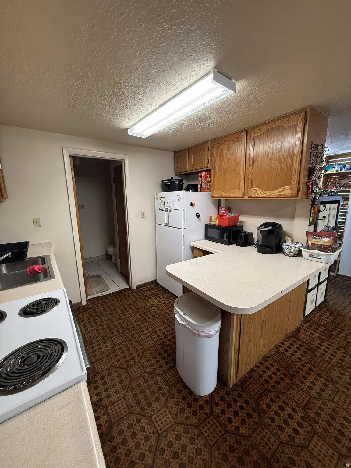 Kitchen featuring wood-finish cabinetry, a white electric range, and a breakfast bar with a light-colored countertop