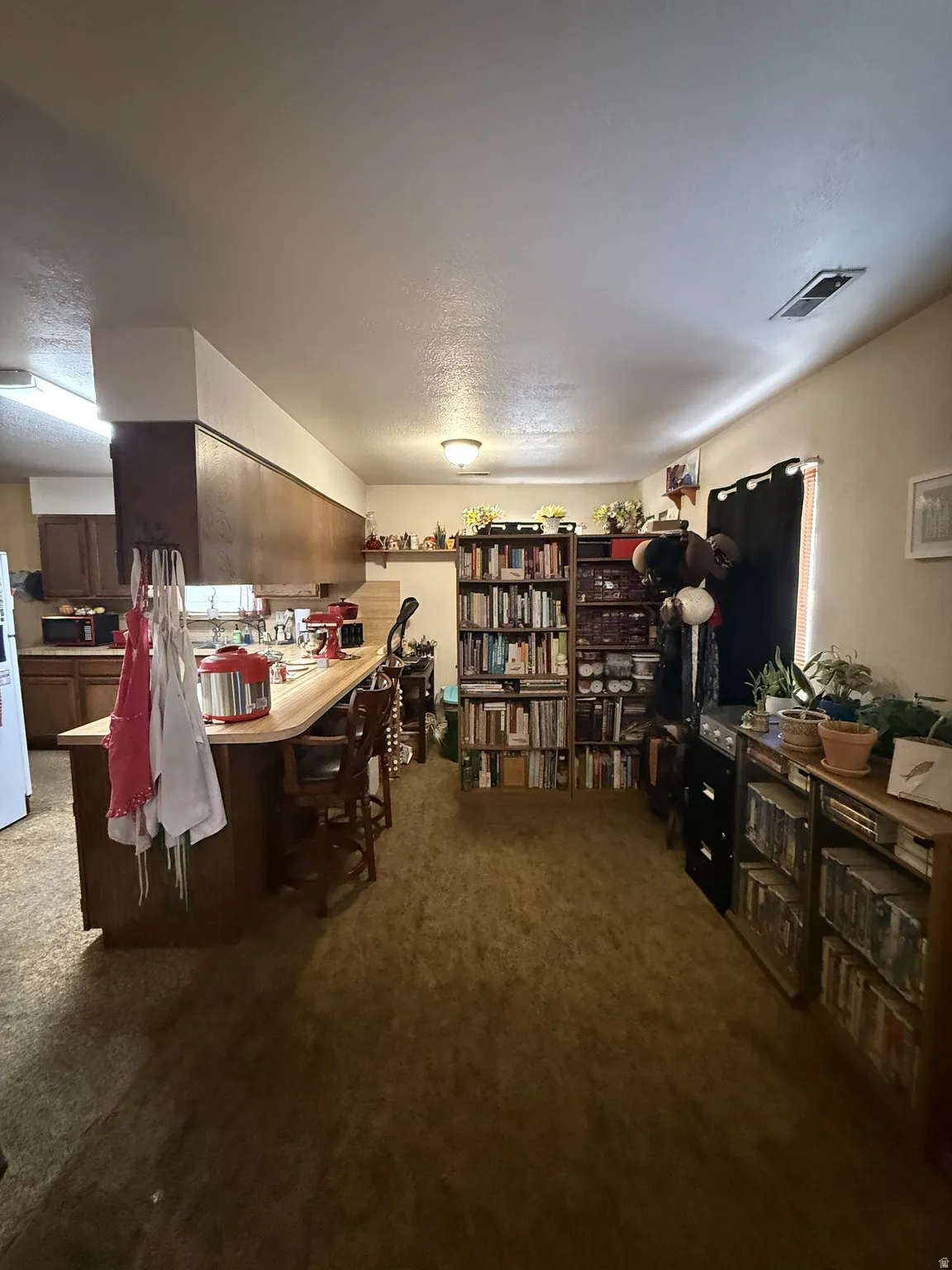 Open-concept kitchen and living area featuring wood-finish cabinetry, a breakfast bar with a wood-finish countertop, and integrated ceiling lighting